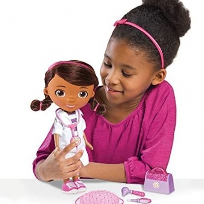 Menina a brincar com boneca médica castanha com acessórios médicos.