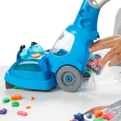 Aspirador de brinquedo azul com massa Play-Doh colorida e uma criança a brincar