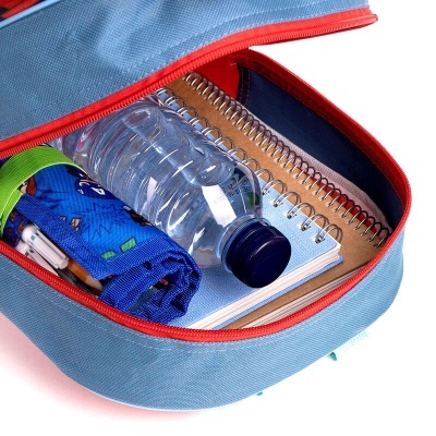 Mochila azul aberta com friso vermelho contendo objeto e cadernos