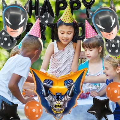 Balões de festa com personagem Batman e letras HAPPY numa festa infantil ao ar livre