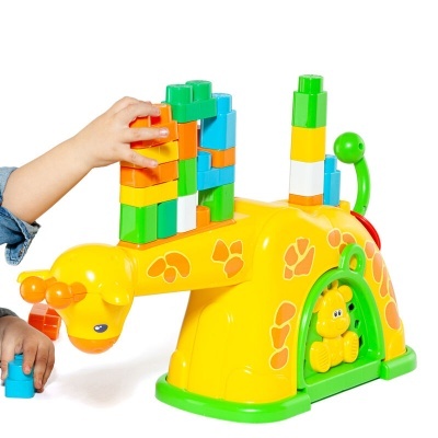 Brinquedo infantil girafa amarelo com blocos coloridos empilhados no dorso