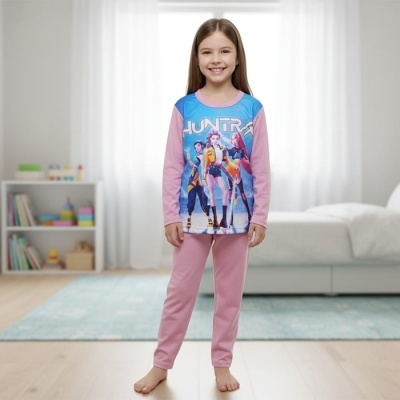 Pijama infantil rosa e azul com estampa de personagens e texto HUNTRA, com calças cor-de-rosa, em quarto iluminado