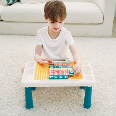 mesa de brincar para crianças com peças numeradas e menino sentado no tapete branco