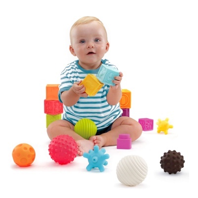 Bebé com brinquedos de blocos macios e bolas coloridas em fundo branco