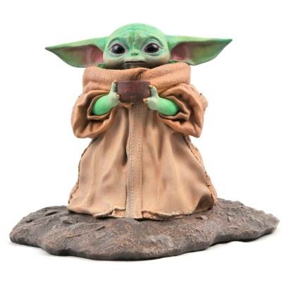 Figura decorativa Baby Yoda (Grogu) com casaco castanho claro segurando tigela sobre base de pedra