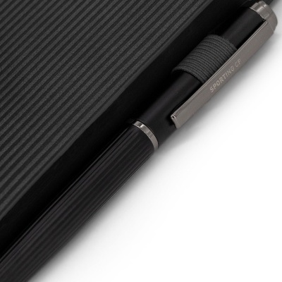 Caneta preta com clip metalizado SPORTING CP ao lado de objeto preto com textura de linhas