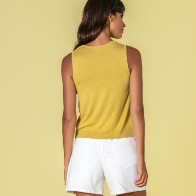 Mulher de costas com top amarelo e calções brancos