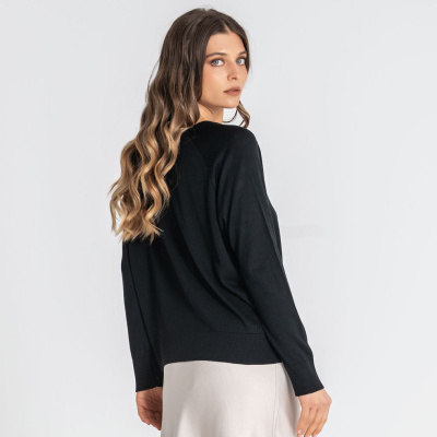 Mulher de costas com camisola preta e saia bege clara