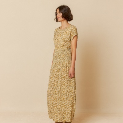 Vestido comprido amarelo floral com mangas curtas usado por mulher de pé