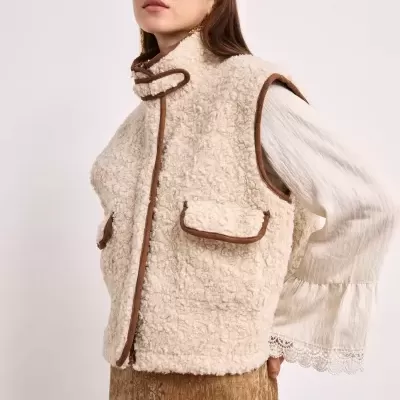 Colete de pelo sintético bege com acabamento castanho e bolsos com aba