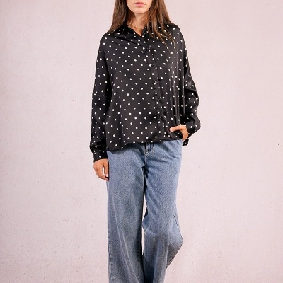 Mulher com camisa preta de bolinhas brancas e calças jeans largas azuis