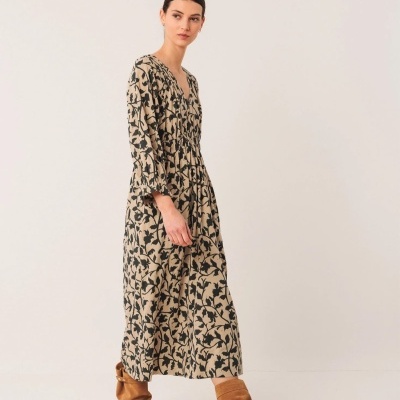 Vestido comprido bege com padrão floral preto e botas castanhas.