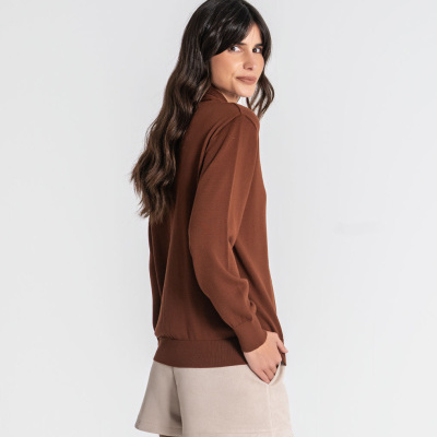 Mulher de costas e lado, camisola castanha e calções bejes em fundo branco