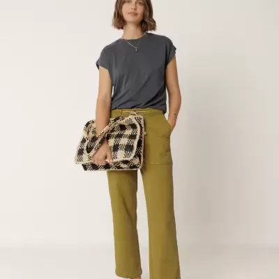 Mulher vestida com roupa casual, segura mala grande com padrão xadrez.