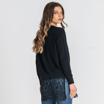 Mulher de costas a usar casaco preto com renda e jeans azul