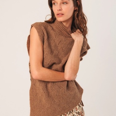 Camisola de malha castanha sem mangas com padrão de tranças e vestido floral bege.