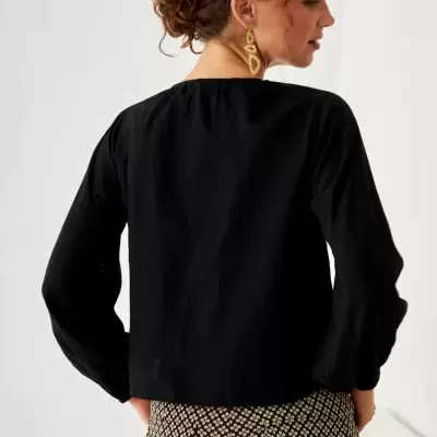 Mulher de costas com blusa preta e calças padrão quadriculado bege e preto