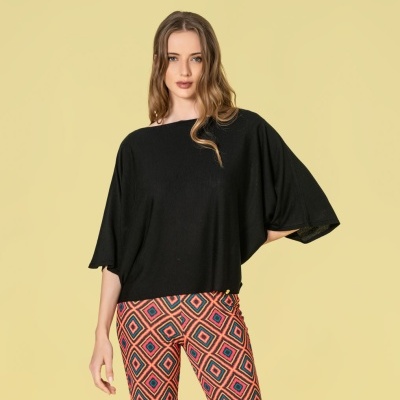 Mulher com camisa preta e calças geométricas coloridas em fundo amarelo