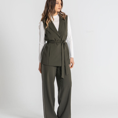 Mulher veste conjunto verde-oliva com colete e calças largas e camisa branca