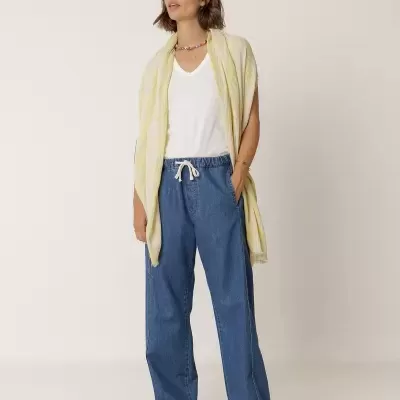 Mulher com t-shirt branca, calças de ganga azul, lenço amarelo claro e ténis brancos