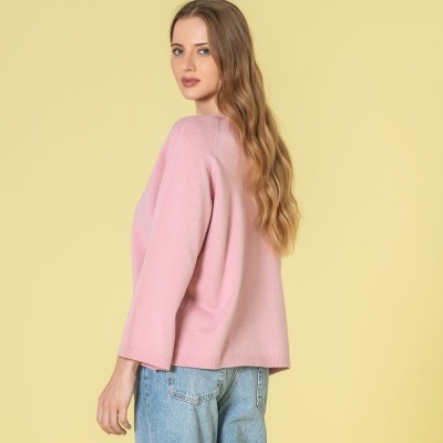 Camisola rosa de malha com calças de ganga azuis em fundo amarelo