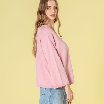 Mulher com camisola rosa e calças de ganga azuis em fundo amarelo