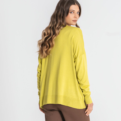 Mulher de costas com camisola amarelo-limão e calças castanhas.