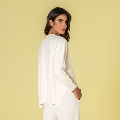 Mulher com camisola e calças brancas em fundo amarelo claro