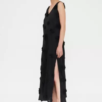 Vestido longo preto com aplicações de flores e fenda lateral usado por modelo