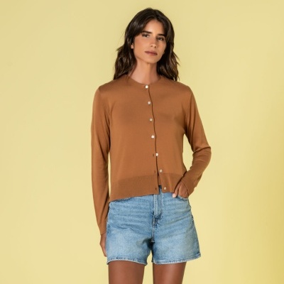 Mulher de cardigan castanho e calções de ganga azul claro num fundo amarelo