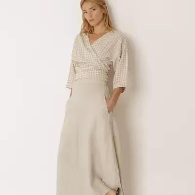 Mulher com top xadrez bege e saia comprida bege com sandálias castanhas