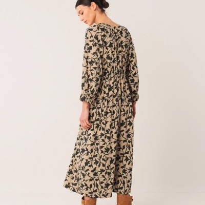 Vestido comprido floral bege e preto com botas castanhas.