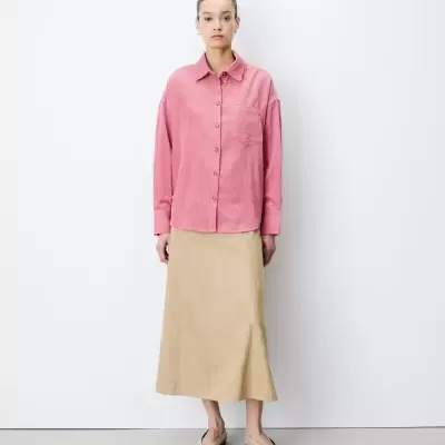 Mulher com blusa rosa de corduroy e saia bege