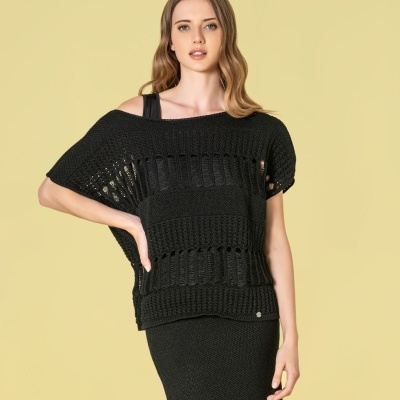 Mulher com roupa preta de malha com padrão de aberturas.