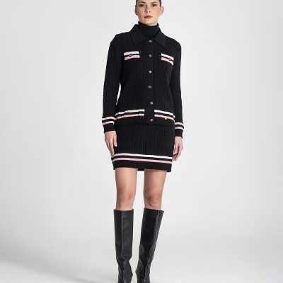 Mulher com conjunto de malha preto com riscas brancas e rosa e botas pretas de cano alto.