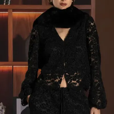 Mulher vestindo conjunto preto em renda com cachecol de pelo preto em ambiente interior