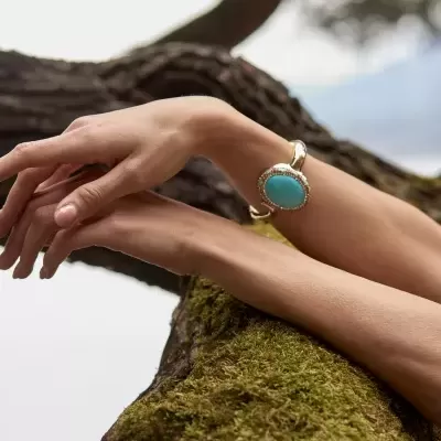 Bracelete dourado com pedra turquesa no pulso da pessoa