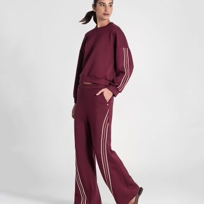 Conjunto de desporto feminino bordo com riscas brancas e calças largas.