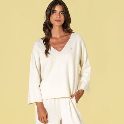 Mulher com camisola de malha creme e calças largas da mesma cor