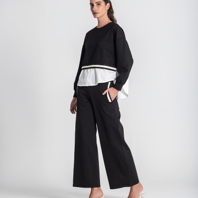 Modelo feminina com conjunto preto e branco e sapatos brancos