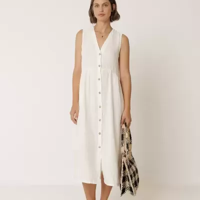 Mulher com vestido midi branco e mala estampada a segurar a mala