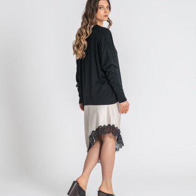 Mulher com camisola preta e saia bege com renda preta, sapatos de salto alto