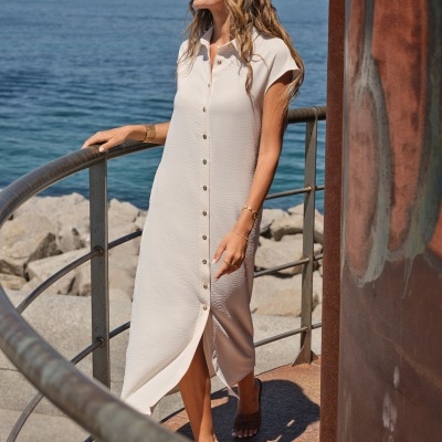 Vestido midi branco com botões e óculos de sol à beira-mar