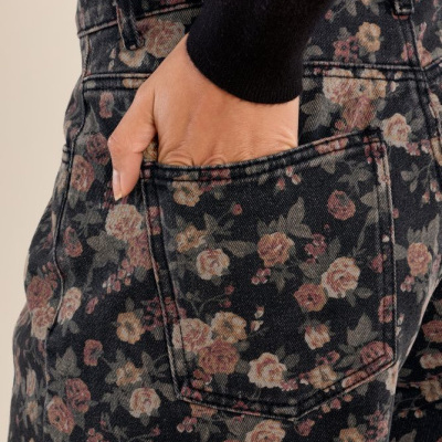 Calças de ganga florais com mão no bolso e camisola preta