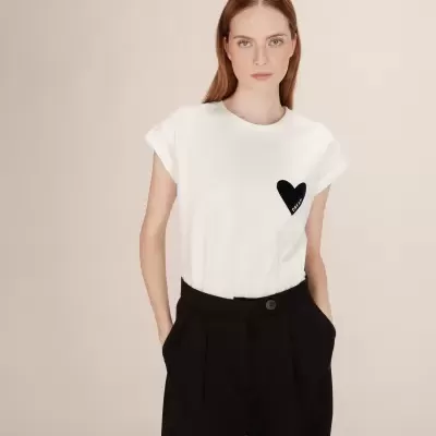 Mulher a usar t-shirt branca com coração preto e calças pretas