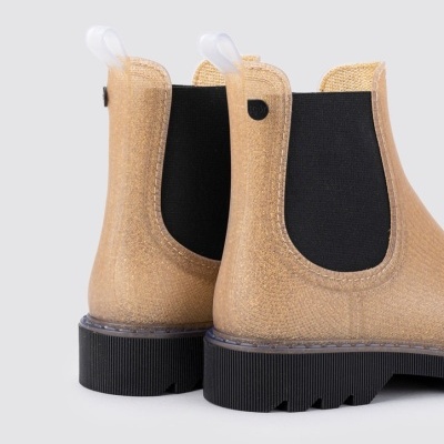 Botas tipo Chelsea semi-transparentes bege com elástico preto e sola preta sobre fundo claro