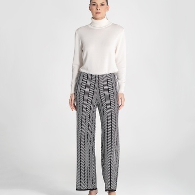 Mulher com camisola branca e calças com padrão preto e branco