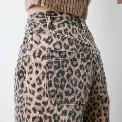 Calças de ganga com padrão animal print e camisola castanha.