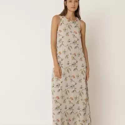 Vestido comprido bege com flores coloridas e sandálias castanhas.