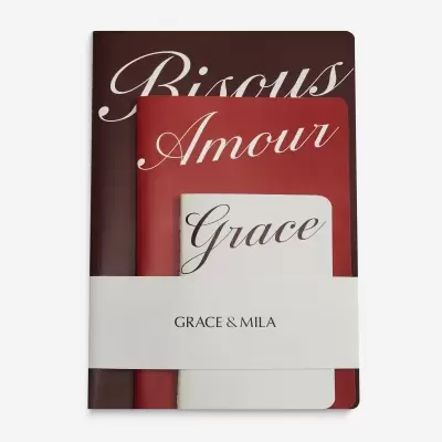 Três cadernos com capas nas cores castanho, vermelho e branco com letras cursivas e faixa com texto GRACE & MILA